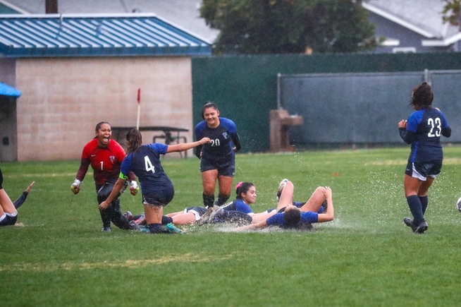 Women's soccer players celebrate after winning their game in penalty kicks